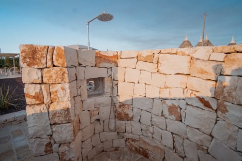 Cortile in pietra dell'hotel Trulli Life a Ostuni con caratteristici tetti conici trulli e architettura rustica tradizionale