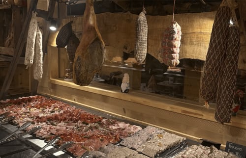 Chez Francine charcuterie display with cured meats, sausages, and hanging products in Notre Dame de Bellecombe