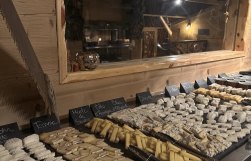 Cheese display window at Chez Francine in Notre Dame de Bellecombe, France showing various French cheeses with labels.