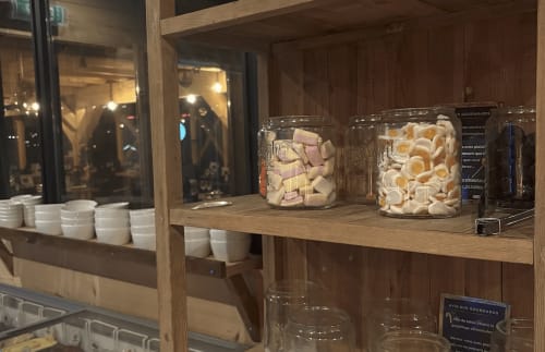 Chez Francine display case with white cups, glass jars of pastries and macarons, Notre Dame de Bellecombe