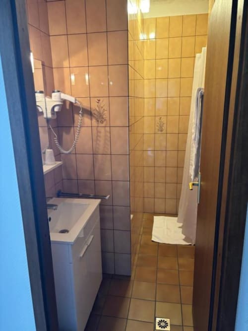 Salle de bain moderne de l'hôtel Le S'Y avec lavabo, douche et murs carrelés à Seingbouse
