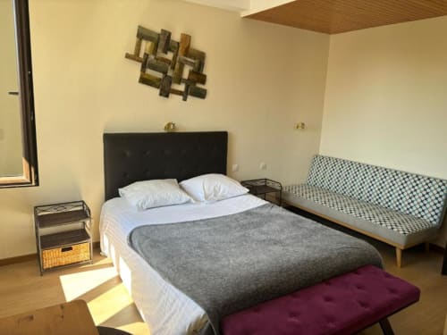 Family room at Hôtel Restaurant Le S'Y featuring queen bed with black headboard, sofa bed, nightstand, and garden view in