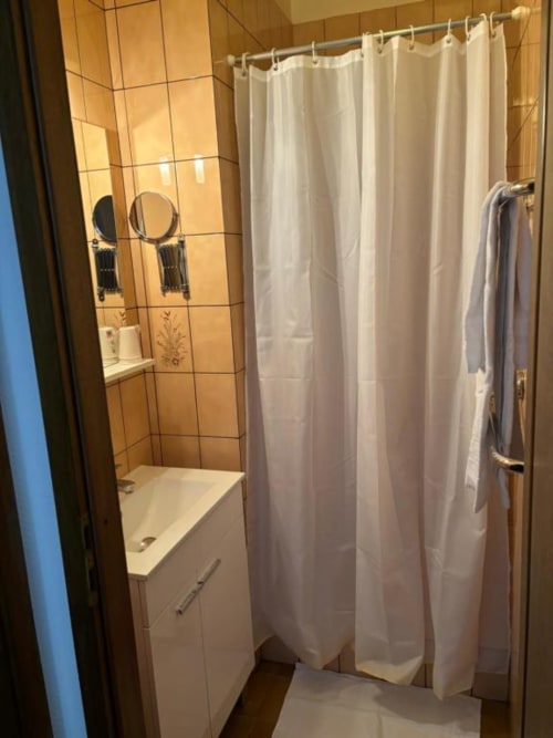 Modern bathroom at Hôtel Restaurant Le S'Y with white shower curtain, vanity sink, and heated towel rack in Seingbouse