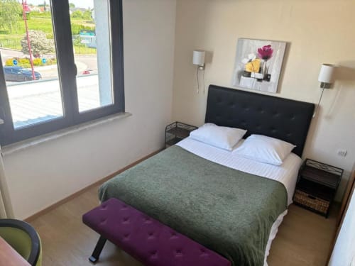 Chambre double moderne à l'Hôtel Restaurant Le S'Y avec vue sur le jardin, tête de lit noire, parure verte et parquet