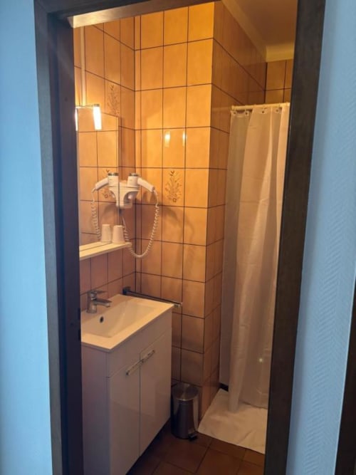 Salle de bains moderne à l'Hôtel Restaurant Le S'Y avec douche aux carreaux orange, meuble vasque blanc et équipements