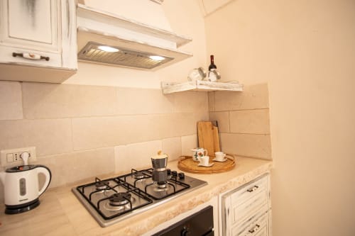 Angolo cucina dell'hotel Trulli Life a Ostuni con fornello a gas, mobili bianchi e rivestimento in piastrelle beige