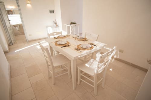 Luminosa zona pranzo nella stanza Trullamie Terra Rossa di Trulli Life, Ostuni, con tavolo bianco, sedie e mise en place