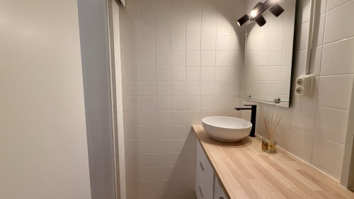 Cuarto de baño moderno en el apartamento Karina 6C de Holidays Costa Brava, Girona con azulejos blancos, lavamanos de cerámica y tocador de madera