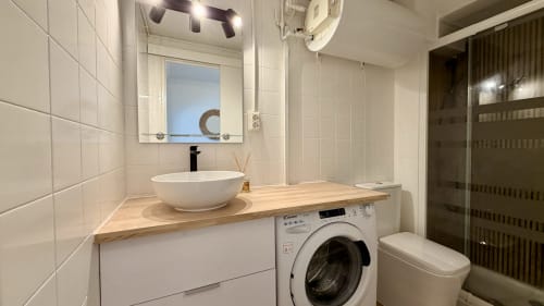 Baño moderno con azulejos blancos, mueble de madera, lavamanos redondo, lavadora y ducha oscura en Holidays Costa Brava