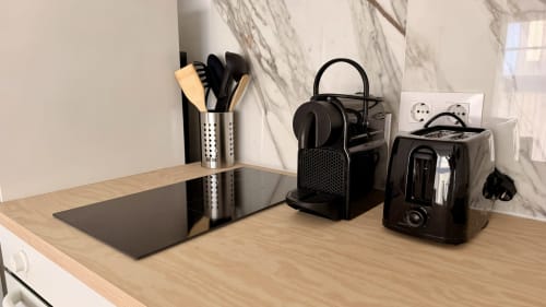 Moderno mostrador de cocina en Holidays Costa Brava con portátil, cafetera y utensilios de cocina en apartamento de Girona.