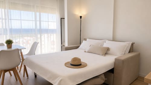 Dormitorio luminoso en Holidays Costa Brava con vista al río, mobiliario moderno y sombrero de paja sobre la cama