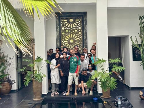 Group of guests and staff posing together at Riad 191's courtyard in Marrakech, surrounded by lush green plants and
