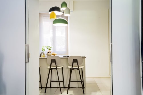 Moderno banco bar nella Zen Seaside Apartment di Genova, con lampade a sospensione colorate e sgabelli neri