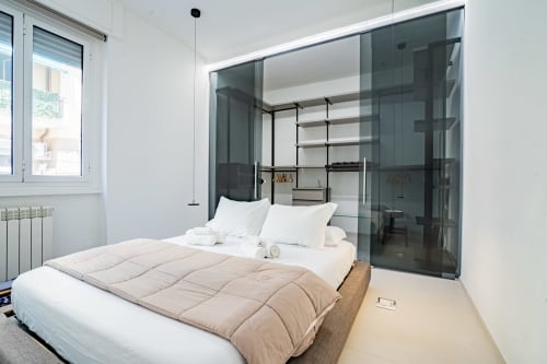 Camera da letto moderna in Zen Seaside Apartment, Genova con letto queen, parete in vetro e arredamento minimalista