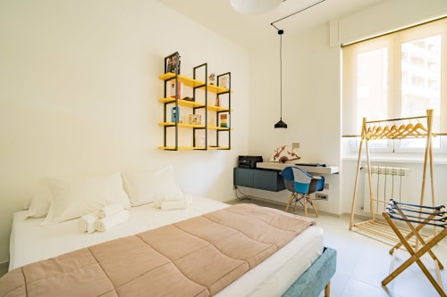 Camera da letto luminosa in appartamento Zen fronte mare a Genova con design minimalista, scaffali gialli e arredamento ispirati dal mare