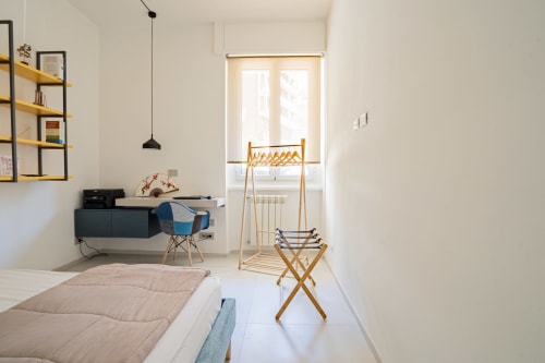 Camera da letto minimalista presso l'Zen Seaside Apartment di Genova con letto, stendibiancheria in legno, scrivania e luce naturale abbondante