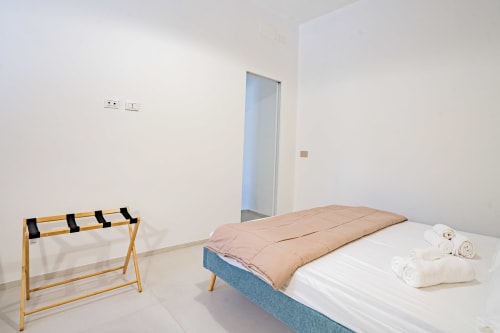 Camera da letto zen fronte mare a Genova con letto, portabagagli e asciugamani bianchi