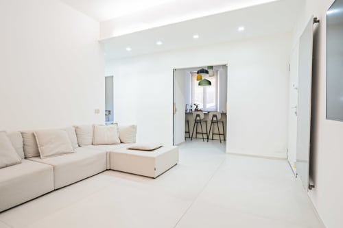Appartamento Zen in riva al mare a Genova: luminoso salotto con divano color crema, angolo cucina e arredi minimalisti