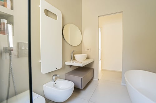 Bagno moderno nell'Apartment Zen Seaside di Genova con lavabi tondi bianchi, specchio circolare e vasca freestanding