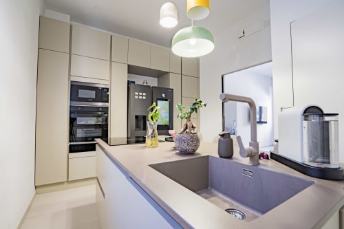 Cucina moderna con mobili bianchi, lavello grigio, luci a sospensione e piante decorative all'Zen Seaside Apartment di Genova
