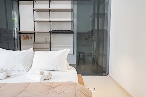 Camera da letto moderna presso Zen Seaside Apartment a Genova con biancheria bianca, scaffalature minimaliste e box doccia in vetro