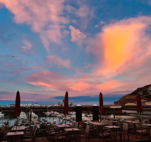 Sunset over Clos Céleste beachfront terrace with red umbrellas and lounge chairs in Étretat, France