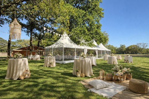 Mariage élégant en plein air au Domaine de La Briandais avec chapiteau crème, tables rondes et décoration rustique sous les chênes