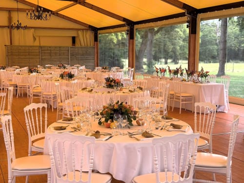 Réception de mariage élégante au Domaine de La Briandais à Missillac avec tables rondes, chaises blanches et vue sur la forêt