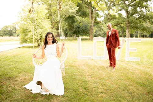 Mariée sur une balançoire avec le marié au Domaine de La Briandais, un lieu de mariage romantique dans un jardin à Missillac