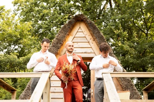 Trois garçons d'honneur en tenue formelle à la cabane en bois au toit moussu du Domaine de La Briandais, Missillac