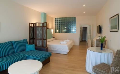 Junior Suite at Posada Torre del Milano in Comillas with turquoise striped sofa, bed, and modern amenities