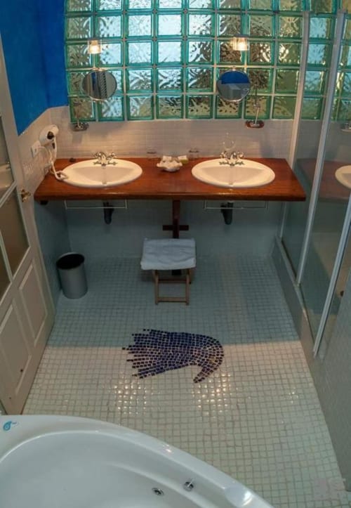 Modern bathroom with dual sinks, decorative tile floor, and large window at Posada Torre del Milano, Comillas