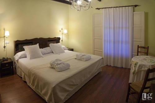 Spacious double room at Posada Torre del Milano in Comillas with ocean views, dark wood bed, cream linens, and garden terrace