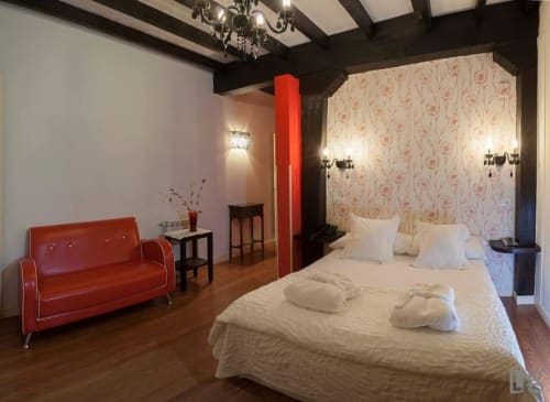 Modern double bedroom at Posada Torre del Milano in Comillas with red sofa, beamed ceiling, and floral wallpaper accent wall