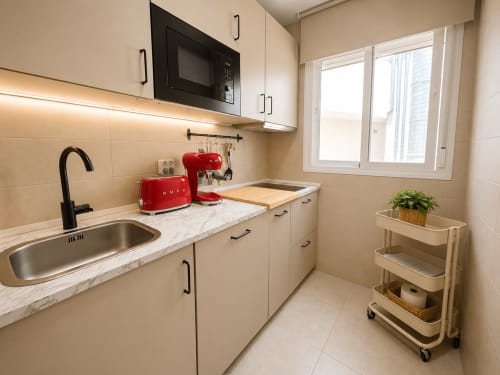 Modern kitchen in Aroma de Azahar apartment at Living Sur, Sanlúcar de Barrameda, with white cabinets, red appliances, marble