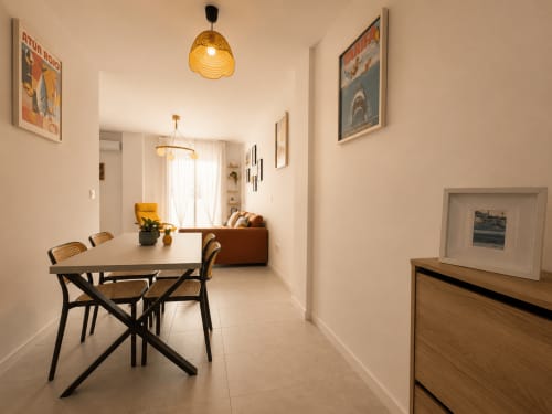 Modern dining area in Aroma de Azahar apartment at Living Sur, Sanlúcar de Barrameda, with table, chairs, and living room