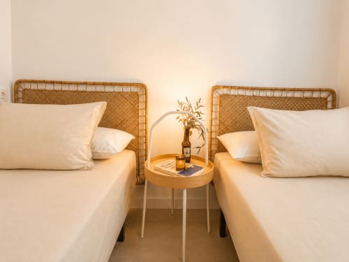 Twin beds with rattan headboards and white linens in Aroma de Azahar apartment at Living Sur, Sanlúcar de Barrameda