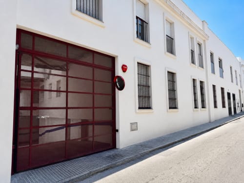 Exterior of Living Sur apartments in Sanlúcar de Barrameda with red garage door and white facade