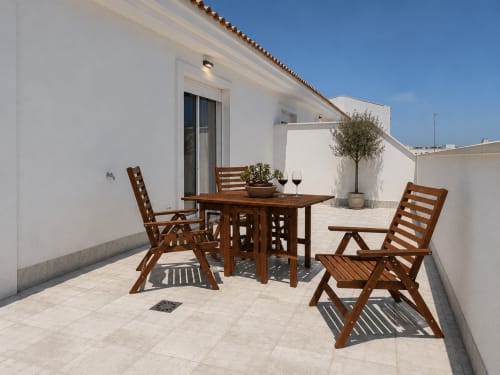 Sunny terrace at Living Sur Sanlúcar with wooden dining furniture, potted plants, and white-walled apartment building