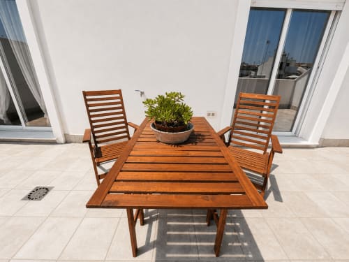 Wooden outdoor dining table with chairs and potted plant on terrace at Living Sur apartment, Sanlúcar de Barrameda