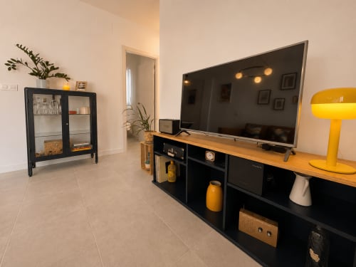 Modern living room at Living Sur apartment in Sanlúcar de Barrameda with flat-screen TV, black storage unit, yellow accent