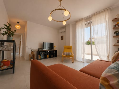 Bright living room in Aroma de Azahar apartment, Sanlúcar de Barrameda, with terracotta sofa, TV, modern pendant lights and