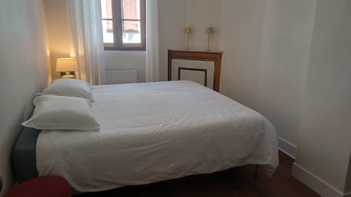 Chambre lumineuse à La Maison de Lezat avec literie blanche, mobilier en bois et vue sur la ville