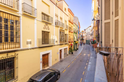 Charming yellow building on narrow Málaga street with traditional Spanish architecture and city views