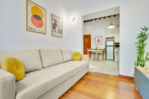 Modern living room in Ayma Apartamento Ollerías, Málaga with cream sofa, yellow accents, and open kitchen view