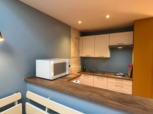 Kitchenette moderne à l'appartement Le Cap, Jardin De Palme, avec meubles en bois clair, micro-ondes et accents bleu-gris