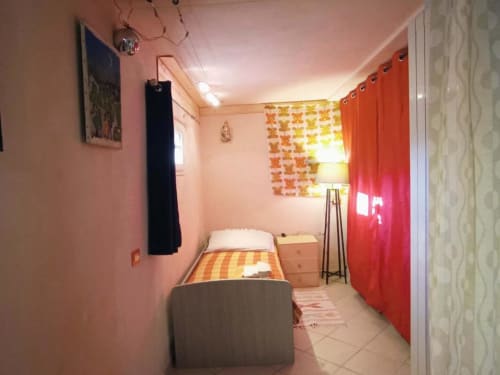 Luminosa camera da letto nell'appartamento La Sorgente a Calice Ligure, con letto singolo, biancheria a righe arancioni, tende rosse e pareti rosa
