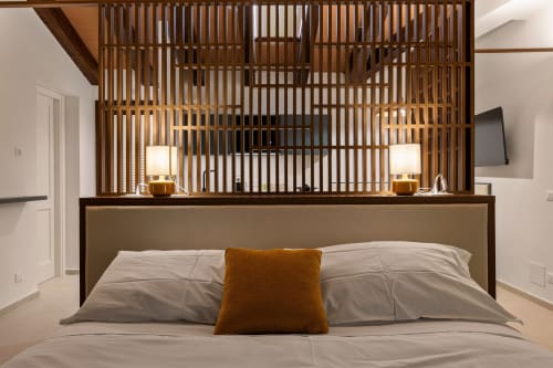 Modern bedroom at Dimora Silva Nature Suites with wooden slat headboard, neutral bedding, and amber accent pillow