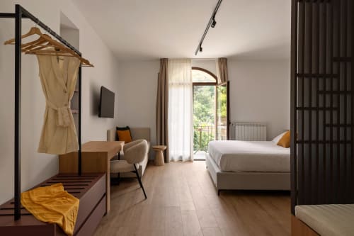 Camera moderna a Dimora Silva Nature Suites con letto, area soggiorno e balcone con vista sulla natura