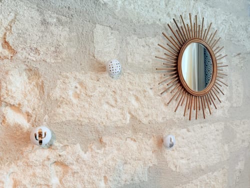 Pared texturizada beige en Hôtel La Suite con espejo decorativo de rayos de sol y acentos de cerámica blanca en la Chambre A.